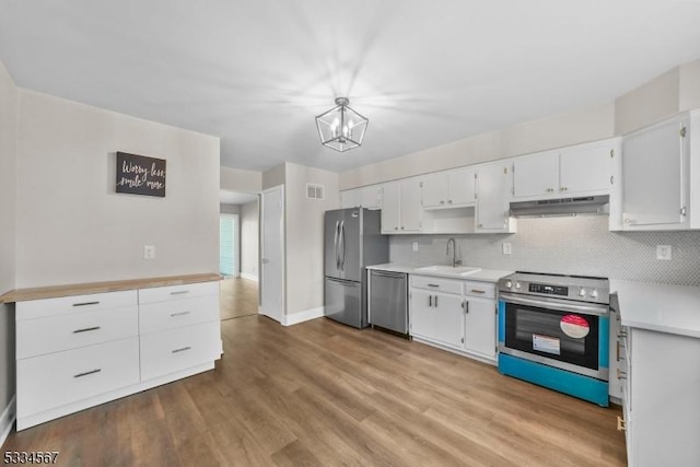 kitchen with appliances with stainless steel finishes, sink, white cabinets, and backsplash