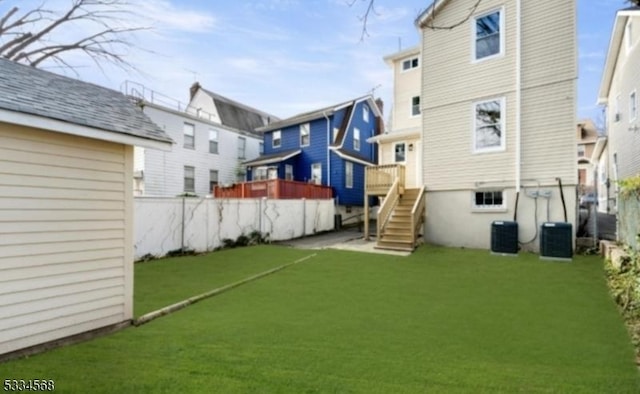 rear view of property featuring cooling unit and a lawn