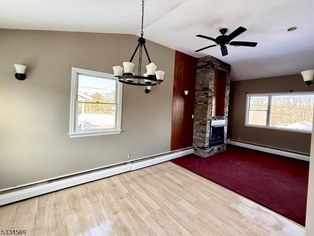 unfurnished living room featuring a baseboard radiator, lofted ceiling, a stone fireplace, and hardwood / wood-style floors