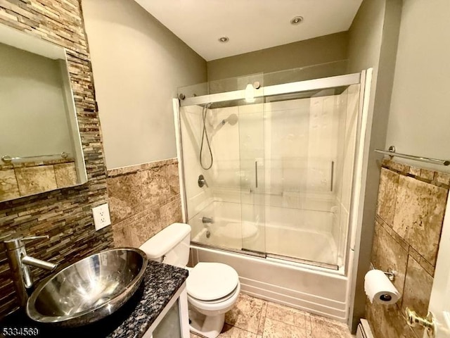 full bathroom with tile walls, vanity, toilet, and combined bath / shower with glass door