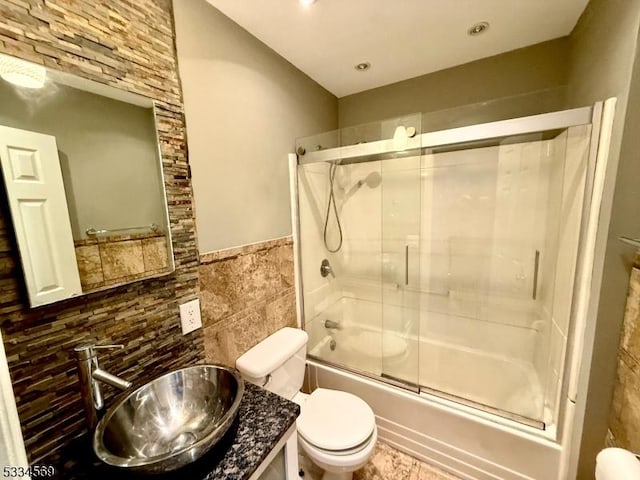 full bathroom with enclosed tub / shower combo, vanity, toilet, and tile walls