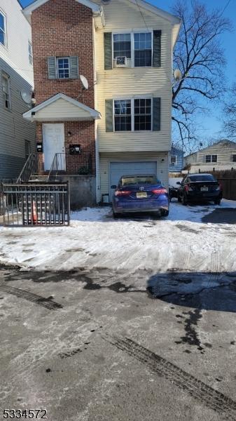 view of front of house featuring brick siding, an attached garage, and fence