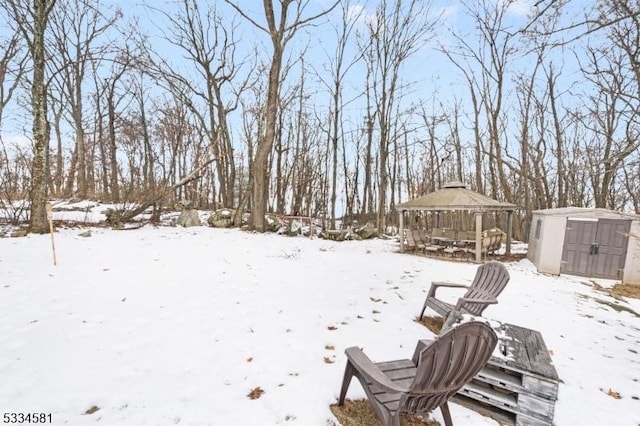 yard covered in snow featuring a gazebo and a storage shed