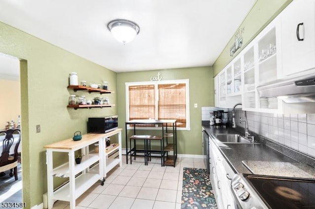 kitchen featuring sink, light tile patterned floors, appliances with stainless steel finishes, white cabinets, and backsplash