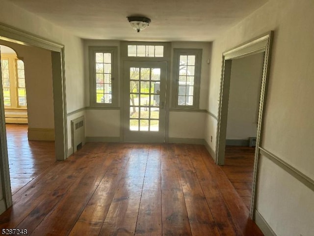 doorway with dark wood-type flooring and radiator heating unit