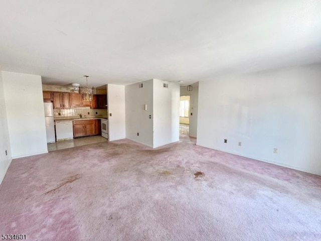 unfurnished living room with light colored carpet and sink