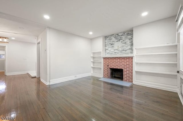 unfurnished living room with dark wood-type flooring, a fireplace, and built in shelves