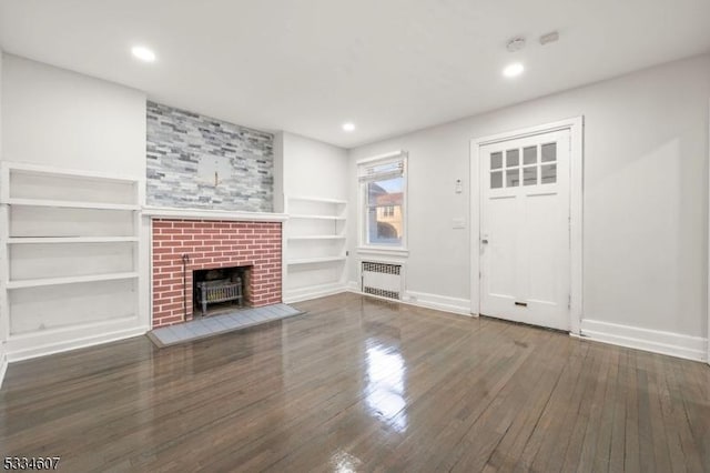 unfurnished living room with radiator heating unit, dark hardwood / wood-style flooring, and built in features