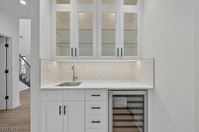 bar featuring white cabinetry, beverage cooler, sink, and decorative backsplash