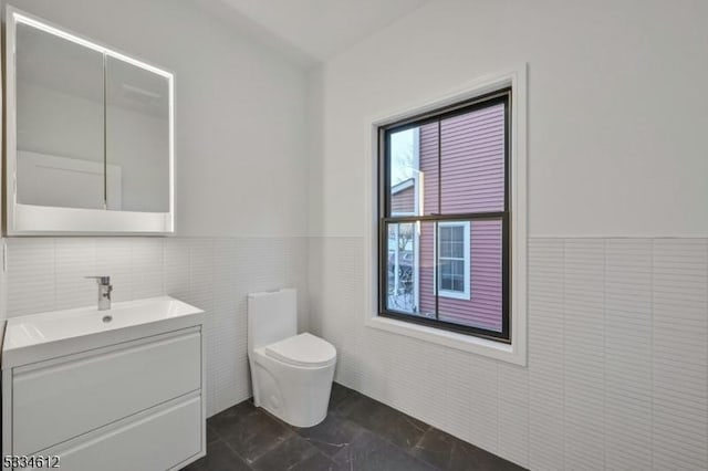 bathroom with vanity, tile walls, and toilet