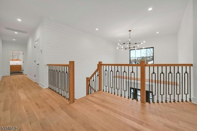 corridor with an inviting chandelier and light wood-type flooring