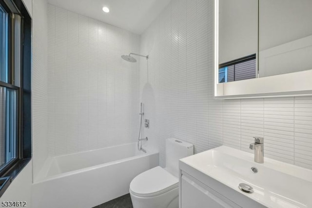 full bathroom featuring tile walls, tiled shower / bath combo, vanity, decorative backsplash, and toilet