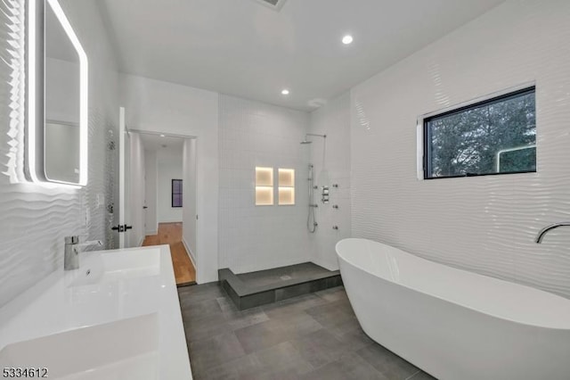 bathroom with tile walls, vanity, and independent shower and bath