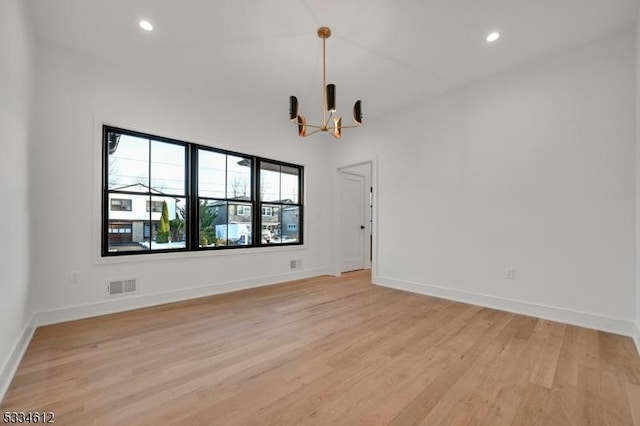 unfurnished room featuring an inviting chandelier and light wood-type flooring