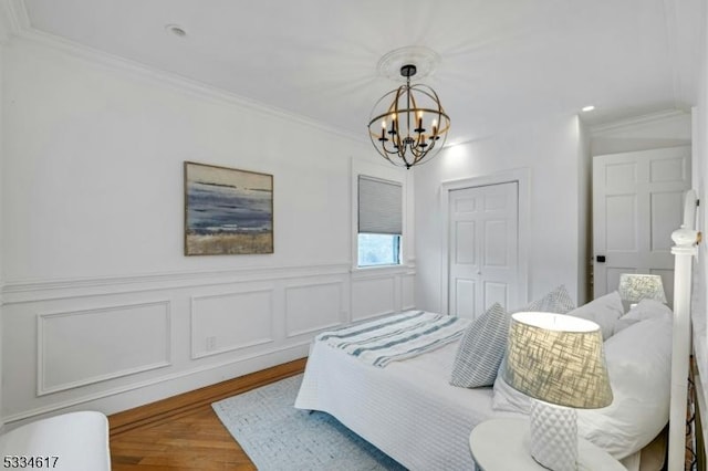 bedroom with crown molding, hardwood / wood-style floors, a chandelier, and a closet