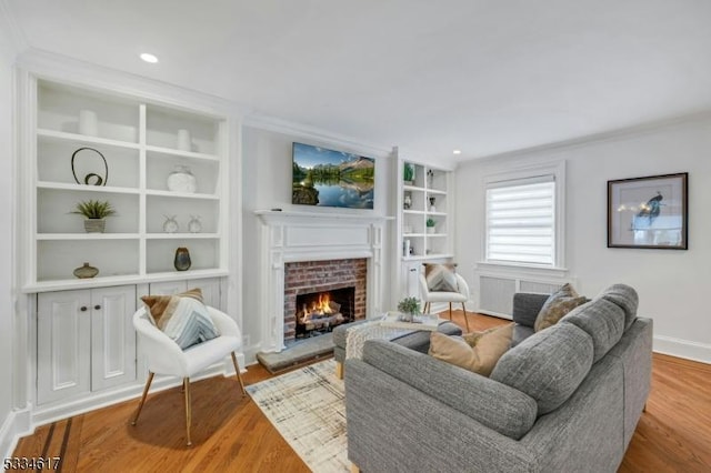 living room with a brick fireplace, built in features, hardwood / wood-style floors, and ornamental molding