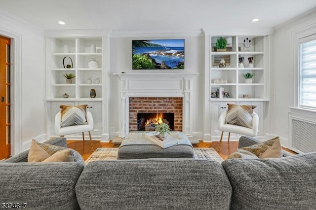 interior space featuring hardwood / wood-style flooring, ornamental molding, a brick fireplace, and built in shelves