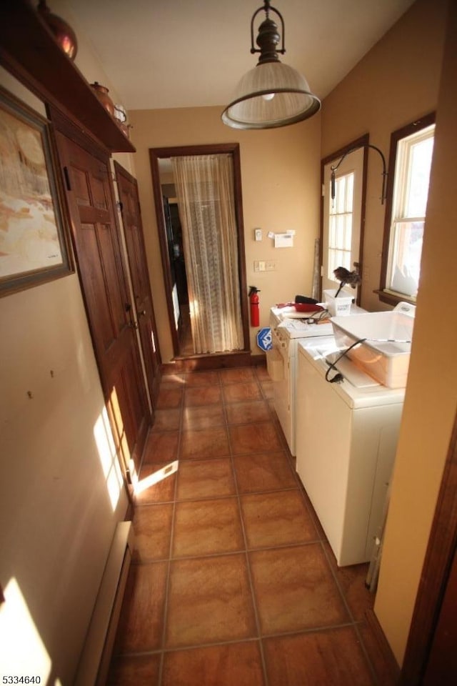 corridor with dark tile patterned flooring, washing machine and dryer, and baseboard heating