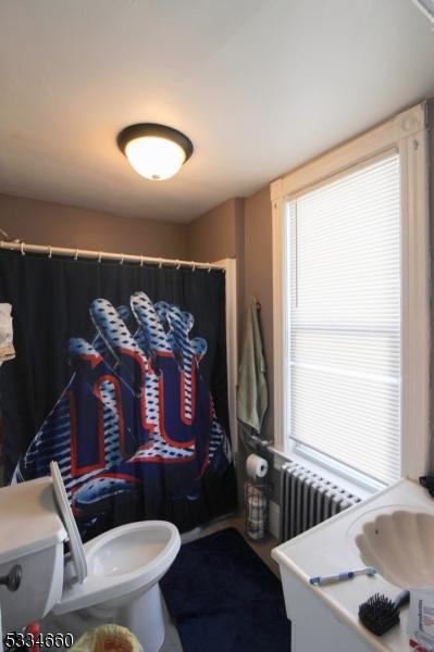 bathroom with toilet, radiator, and sink