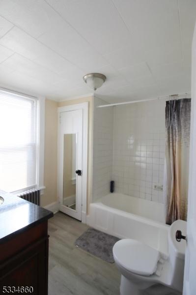 full bathroom featuring vanity, hardwood / wood-style floors, shower / bathtub combination with curtain, and toilet