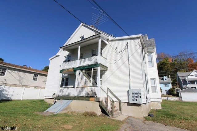 rear view of property featuring a lawn and a balcony