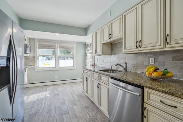 kitchen with dark stone countertops, cream cabinets, stainless steel appliances, and sink