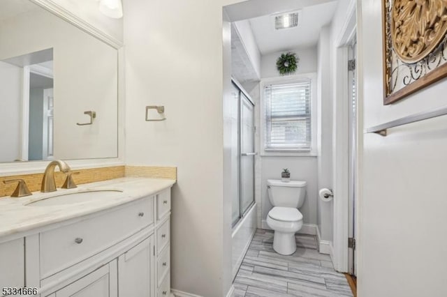 full bathroom featuring vanity, enclosed tub / shower combo, and toilet