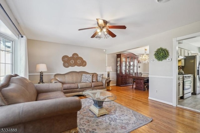 living room with ceiling fan with notable chandelier and hardwood / wood-style floors