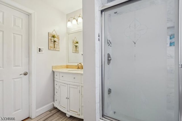 bathroom with walk in shower, vanity, and hardwood / wood-style floors