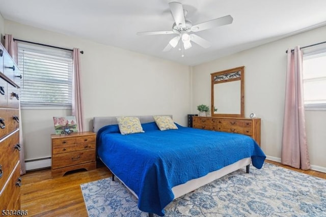 bedroom with hardwood / wood-style flooring, a baseboard radiator, and ceiling fan