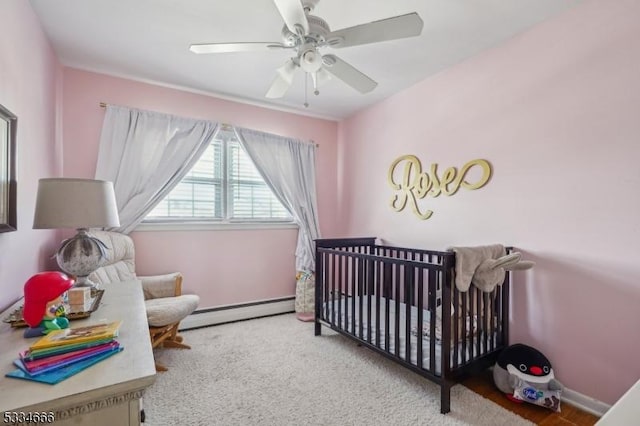 bedroom with ceiling fan, a baseboard radiator, carpet flooring, and a crib