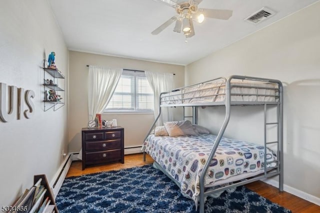 bedroom with ceiling fan, hardwood / wood-style floors, and baseboard heating