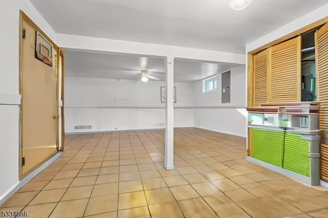 basement with ceiling fan, electric panel, and light tile patterned floors