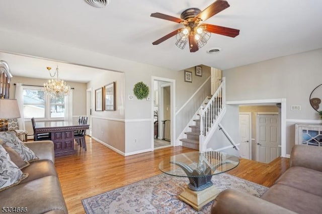 living room featuring ceiling fan with notable chandelier and wood-type flooring