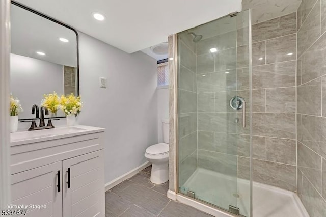 bathroom with vanity, a shower with shower door, and toilet