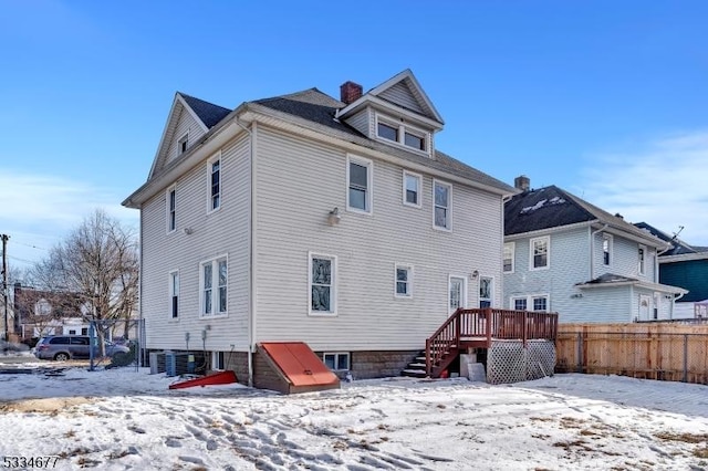 snow covered rear of property with a wooden deck