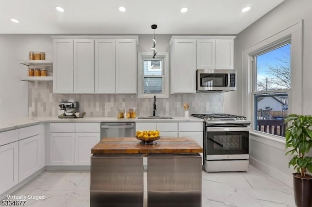 kitchen with sink, hanging light fixtures, white cabinets, and appliances with stainless steel finishes