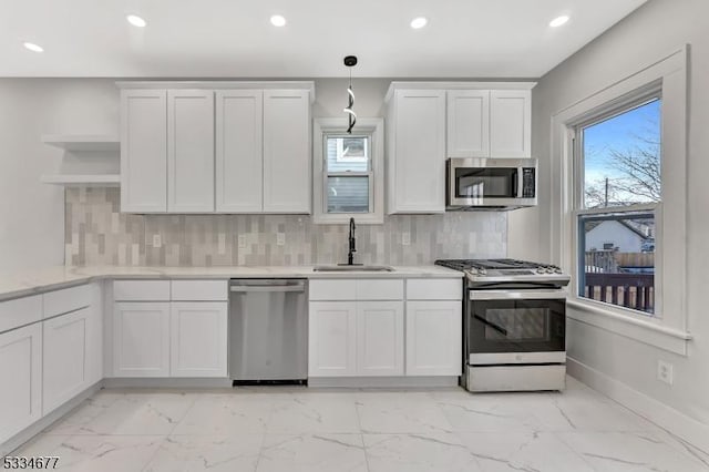 kitchen with stainless steel appliances, sink, white cabinets, and decorative light fixtures