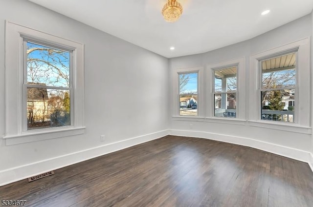 spare room with plenty of natural light and dark wood-type flooring