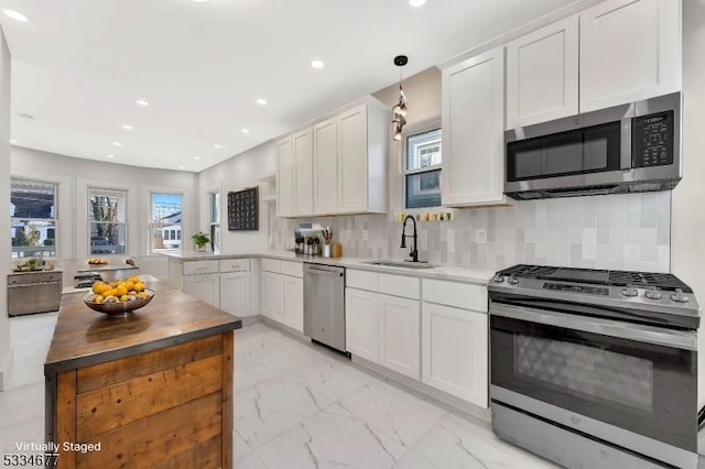 kitchen featuring appliances with stainless steel finishes, decorative light fixtures, white cabinetry, sink, and decorative backsplash