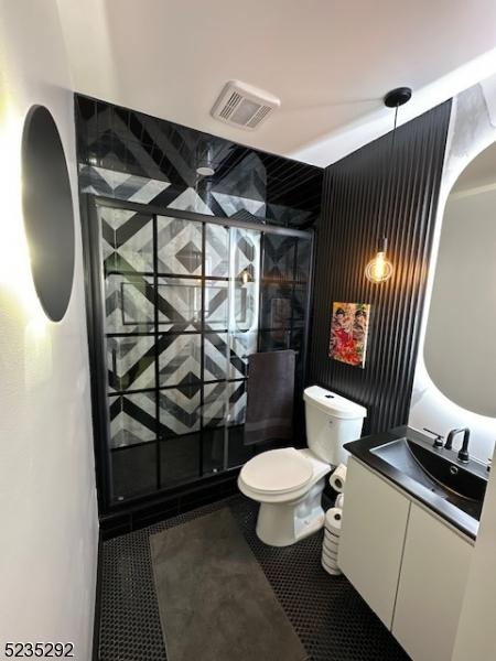 bathroom featuring vanity, toilet, tile patterned floors, and walk in shower