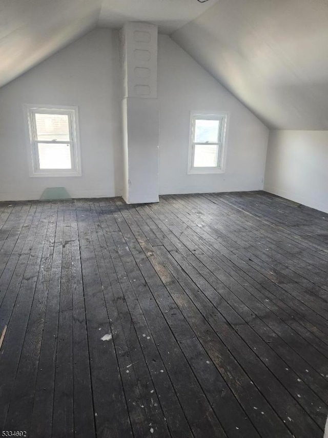 additional living space with vaulted ceiling and dark wood-type flooring