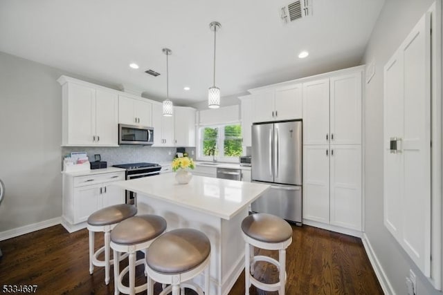 24 Stonybrook Cir, Fairfield Twp, NJ 07004 - kitchen with appliances with stainless steel finishes, dark wood-style flooring, a breakfast bar, white cabinetry, and a kitchen island