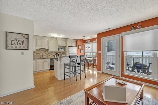 living room featuring sink, light hardwood / wood-style floors, and a textured ceiling