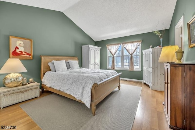 bedroom featuring vaulted ceiling, a textured ceiling, and light wood-type flooring