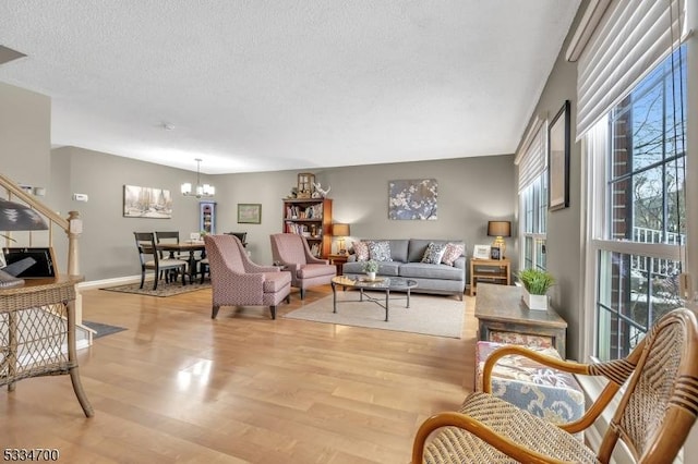 living room featuring an inviting chandelier, a textured ceiling, and light wood-type flooring