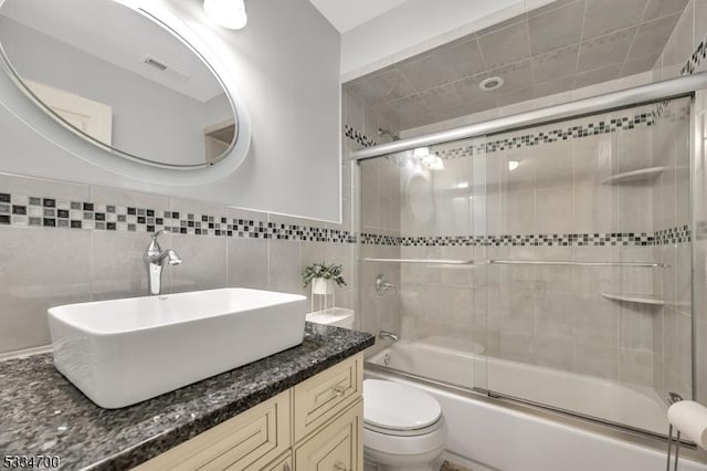 full bathroom featuring vanity, toilet, and combined bath / shower with glass door