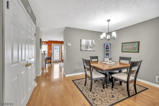 dining room featuring a chandelier, a textured ceiling, and light wood-type flooring