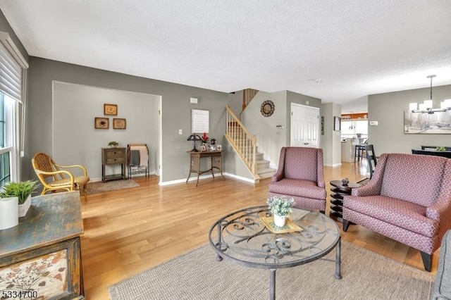 living room with hardwood / wood-style floors, a textured ceiling, and an inviting chandelier