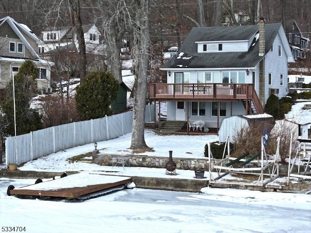 snow covered back of property with a wooden deck